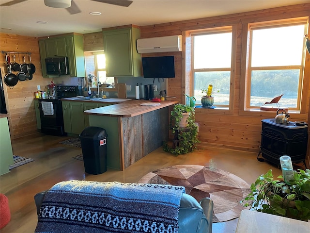 kitchen featuring black appliances, a wall mounted AC, green cabinets, and wooden walls