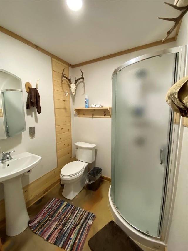 bathroom featuring sink, toilet, a shower with shower door, and ornamental molding