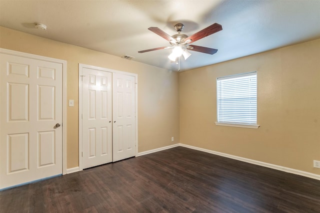 unfurnished bedroom with ceiling fan and dark wood-type flooring