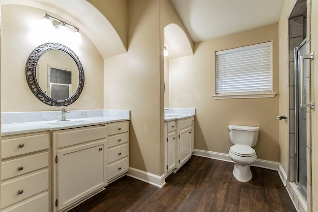 bathroom with wood-type flooring, toilet, vanity, and an enclosed shower