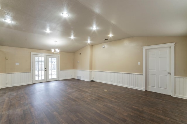 empty room with french doors, a textured ceiling, dark hardwood / wood-style floors, a chandelier, and lofted ceiling