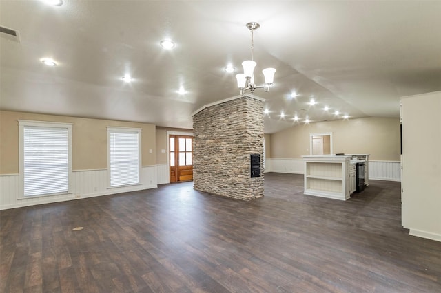 unfurnished living room featuring a notable chandelier, dark hardwood / wood-style flooring, a stone fireplace, and vaulted ceiling