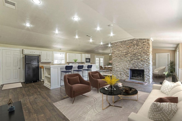 living room featuring a stone fireplace, dark hardwood / wood-style floors, and lofted ceiling