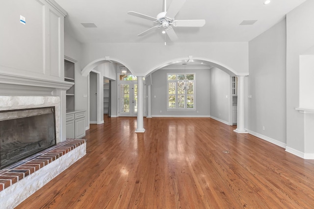 unfurnished living room with decorative columns, a brick fireplace, and hardwood / wood-style floors