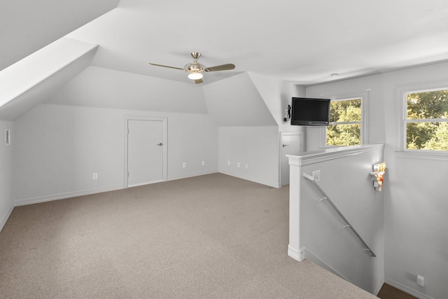 additional living space featuring ceiling fan, light colored carpet, and vaulted ceiling