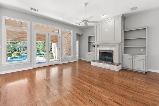 unfurnished living room featuring built in features, ceiling fan, french doors, and light wood-type flooring