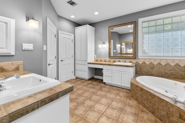 bathroom featuring a relaxing tiled tub, tile patterned floors, and vanity