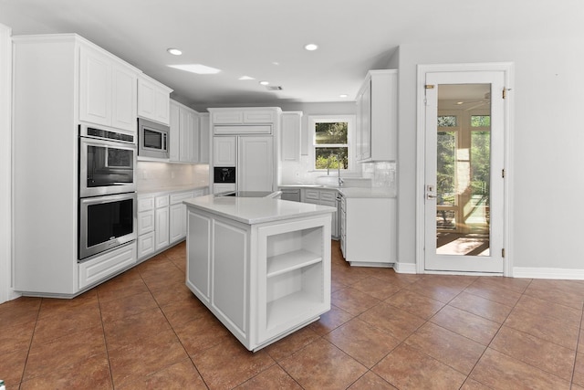 kitchen featuring white cabinets, a kitchen island, built in appliances, and tile patterned flooring