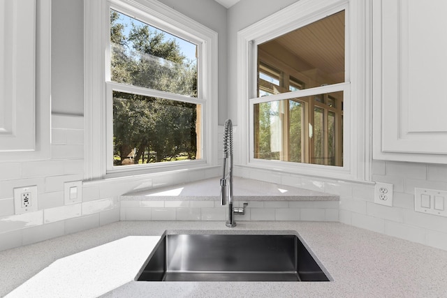 details featuring sink, white cabinetry, light stone countertops, and tasteful backsplash