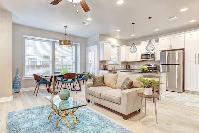 living room featuring ceiling fan, sink, and light hardwood / wood-style flooring