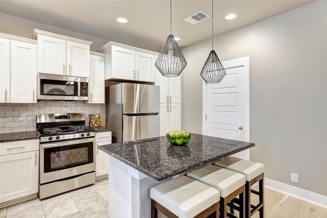 kitchen featuring a kitchen island, white cabinets, decorative backsplash, and appliances with stainless steel finishes