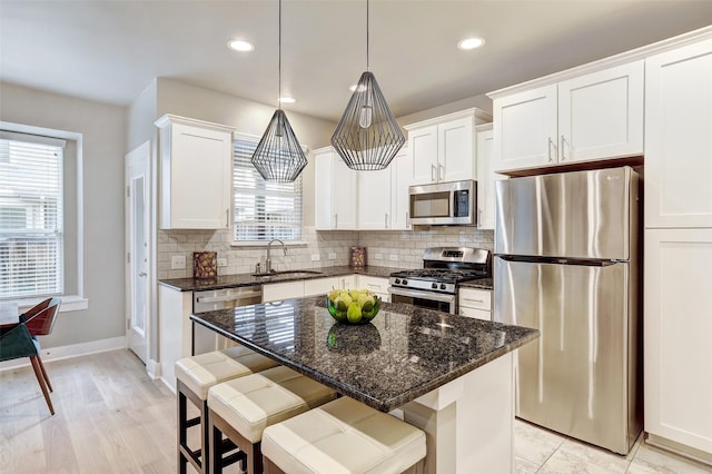 kitchen with sink, white cabinetry, stainless steel appliances, and a kitchen island