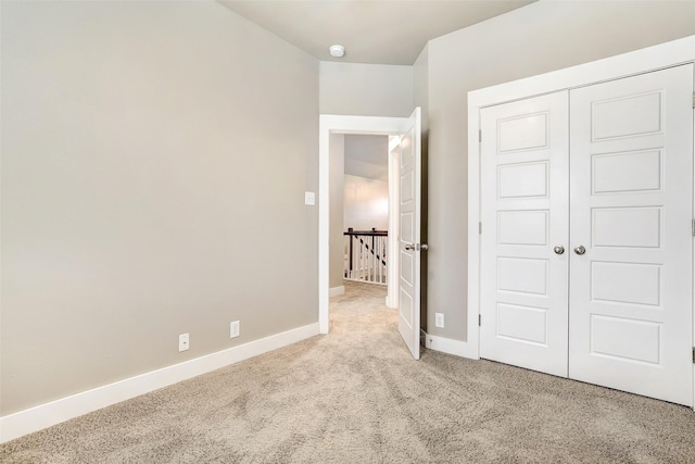 unfurnished bedroom featuring light colored carpet and a closet