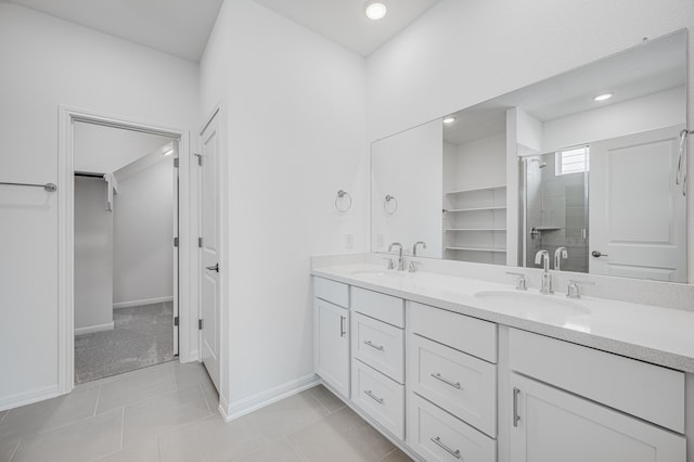 bathroom featuring double vanity, a stall shower, a spacious closet, and a sink