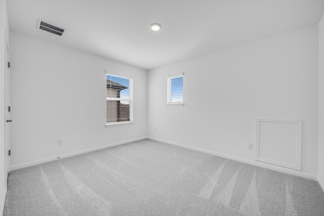 spare room with light carpet, baseboards, and visible vents