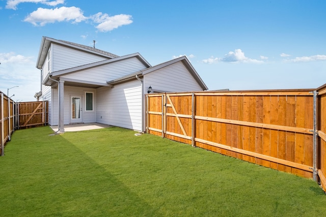 rear view of house featuring a yard, a patio, a fenced backyard, and a gate