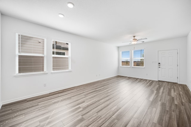 spare room featuring light wood-type flooring, baseboards, and a ceiling fan