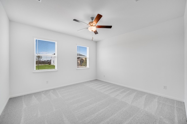 carpeted empty room with a ceiling fan and baseboards