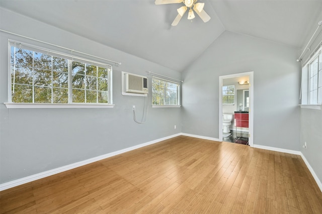 unfurnished room with vaulted ceiling, a healthy amount of sunlight, hardwood / wood-style floors, and an AC wall unit