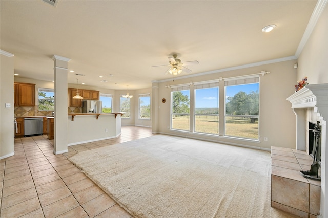 unfurnished living room featuring crown molding, a fireplace, ceiling fan with notable chandelier, and light tile patterned floors