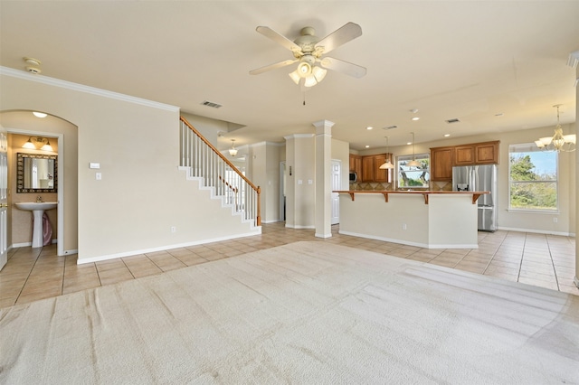 unfurnished living room with crown molding, ceiling fan with notable chandelier, sink, and light tile patterned floors