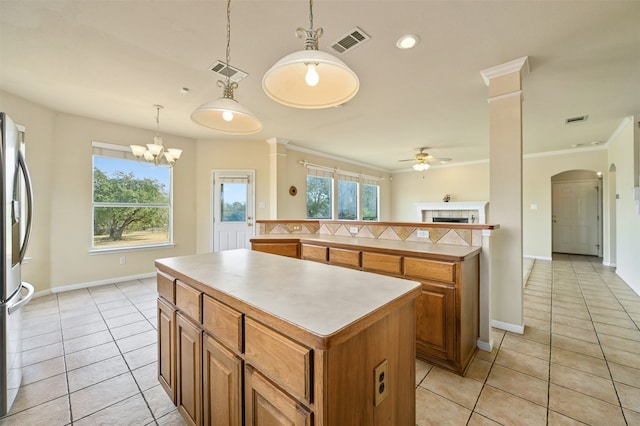 kitchen with hanging light fixtures, a kitchen island, light tile patterned floors, and stainless steel refrigerator