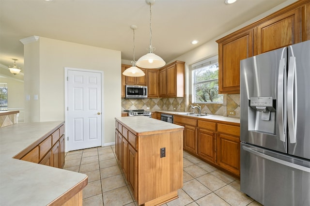 kitchen featuring sink, hanging light fixtures, stainless steel appliances, a kitchen island, and decorative backsplash