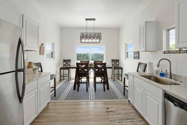 kitchen with light wood-style flooring, white cabinetry, stainless steel appliances, and a sink