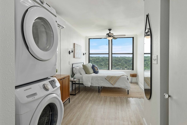 interior space featuring a ceiling fan, baseboards, light wood finished floors, cabinet space, and stacked washer / dryer