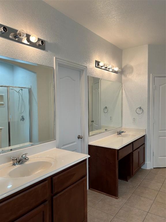 bathroom featuring vanity, a shower with shower door, tile patterned floors, and a textured ceiling