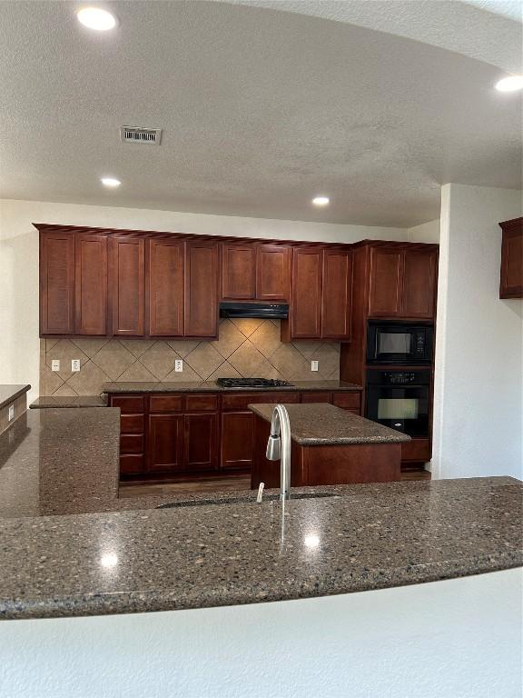 kitchen featuring dark stone countertops, sink, a textured ceiling, and black appliances