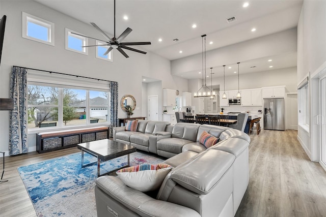 living room with light hardwood / wood-style floors, a high ceiling, and ceiling fan