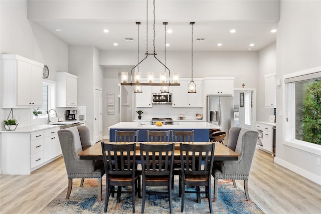 dining area featuring sink, a high ceiling, and light hardwood / wood-style flooring