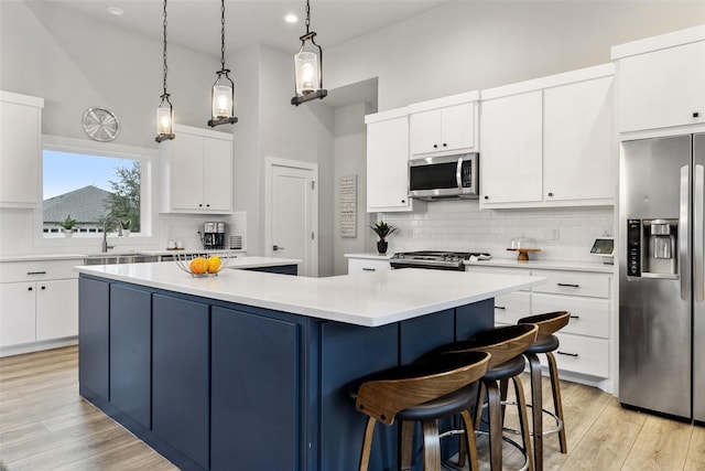 kitchen with white cabinetry, appliances with stainless steel finishes, a center island, and a towering ceiling