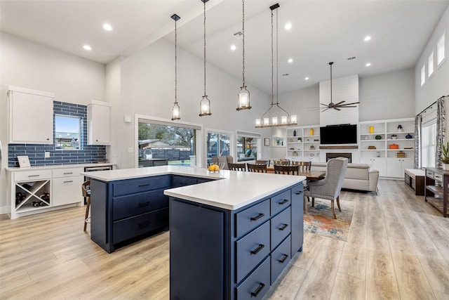 kitchen with white cabinets, a towering ceiling, a center island, and pendant lighting