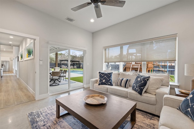 living room featuring ceiling fan and concrete flooring