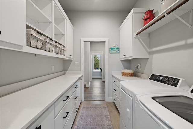 laundry area featuring cabinets, light hardwood / wood-style flooring, and washing machine and clothes dryer