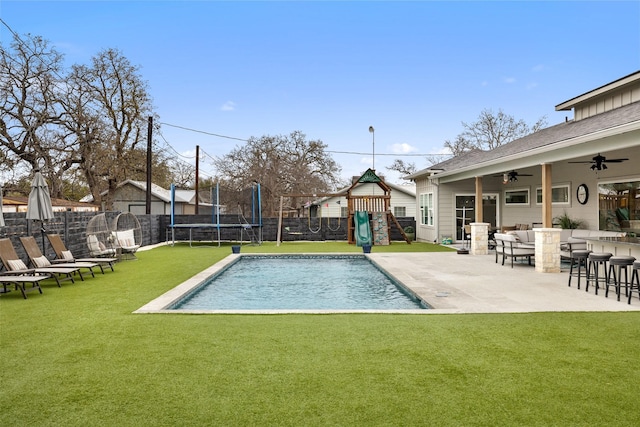 view of pool featuring a bar, a playground, a lawn, and a trampoline