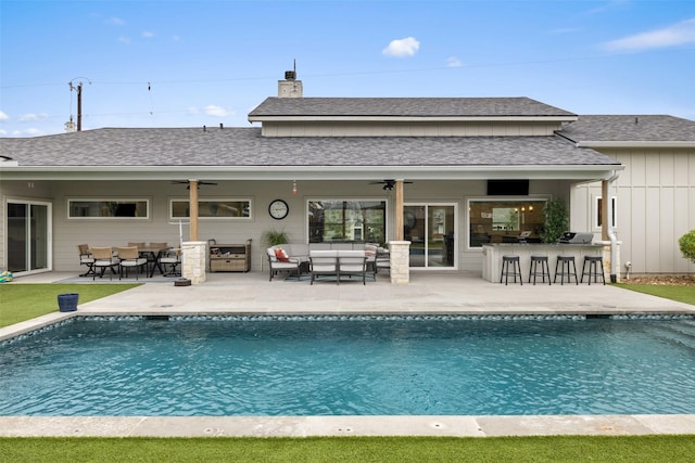 back of house with ceiling fan, a patio area, a bar, and an outdoor hangout area