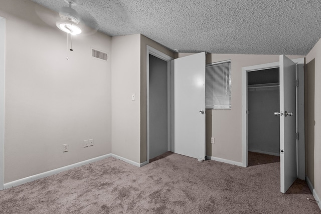 unfurnished bedroom featuring a closet, ceiling fan, light colored carpet, and a textured ceiling