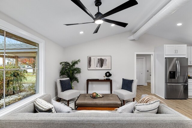 living room with ceiling fan, lofted ceiling, and light wood-type flooring