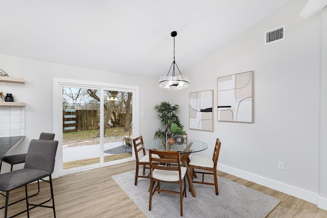 dining area featuring lofted ceiling, a notable chandelier, and light hardwood / wood-style flooring