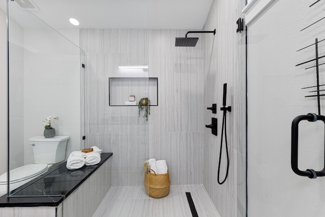 bathroom featuring a shower with door and toilet