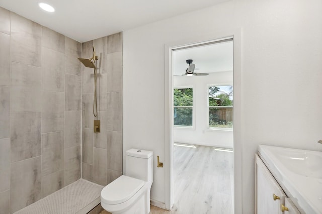 bathroom with vanity, toilet, tiled shower, and hardwood / wood-style floors