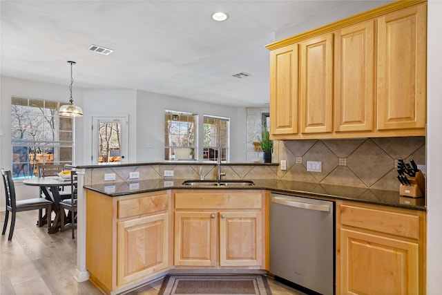 kitchen featuring dishwasher, sink, dark stone countertops, kitchen peninsula, and light wood-type flooring