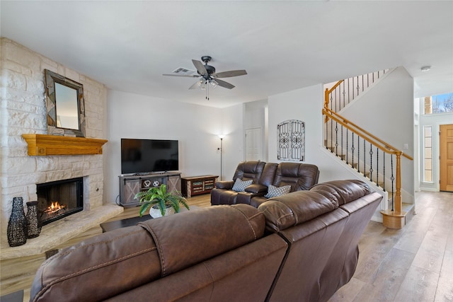 living room featuring ceiling fan, a fireplace, and light hardwood / wood-style flooring