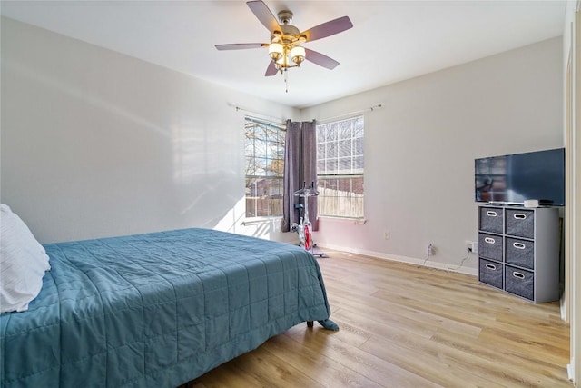 bedroom with light wood-type flooring, baseboards, and a ceiling fan