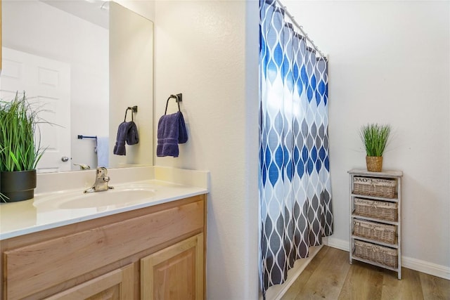 full bath with curtained shower, wood finished floors, vanity, and baseboards