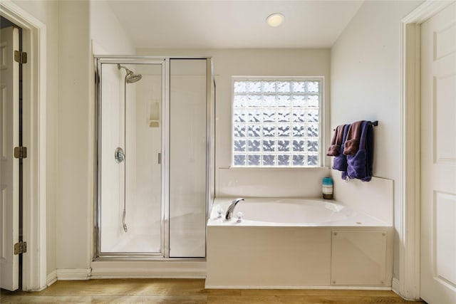 bathroom featuring wood-type flooring and shower with separate bathtub