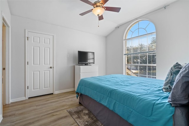 bedroom with a ceiling fan, baseboards, vaulted ceiling, and light wood finished floors